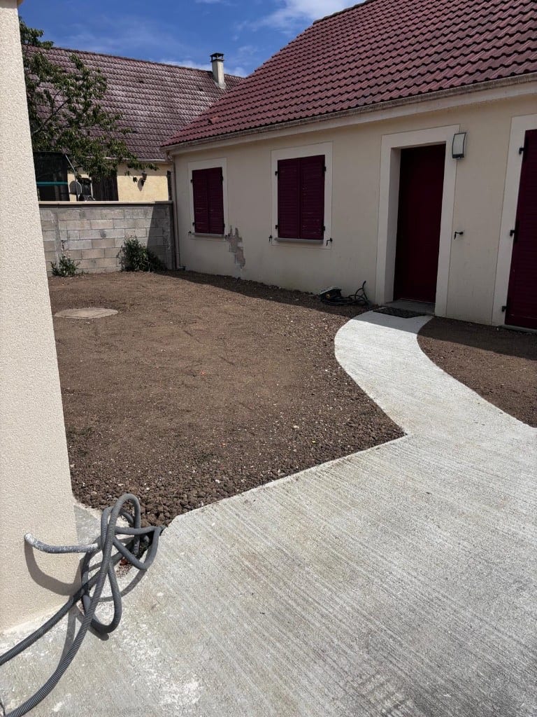 Après : terrain nivelé et allée béton coulée jusqu'à la porte d'entrée