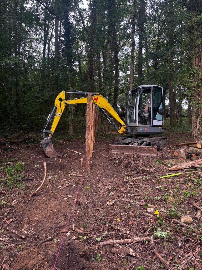 Mini-pelle sur chantier de terrassement en zone boisée